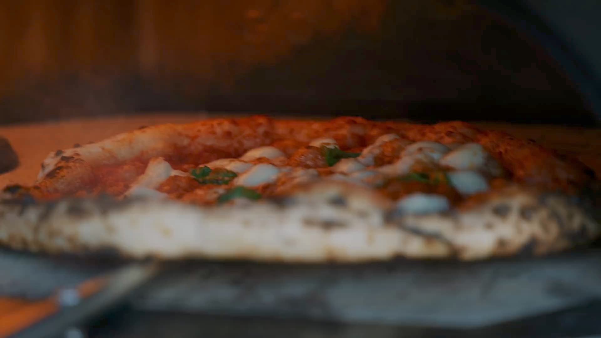 Fresh pizzas coming out of a busy pizza oven